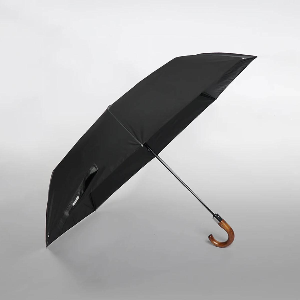 Osoba trzymająca duży parasol składany z wygodną drewnianą rączką